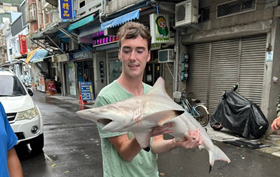 IMAS students visited various markets to select seafood for lunch; among them, American student Jacob McGee was closely examining a shark.