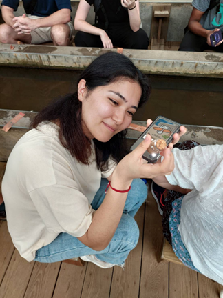 Tolgonai Elemanova, an MA student from the OSCE Academy in Bishkek, Kyrgyzstan, checking gold flakes with a cell phone flashlight.