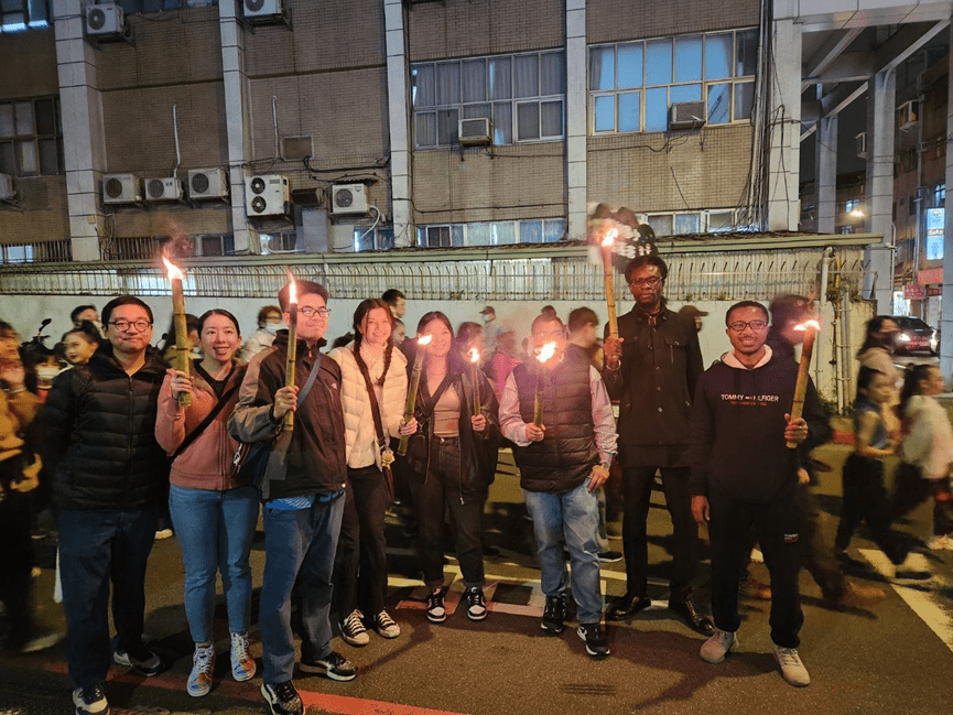 Students and scholars participate in a torch-lit parade along the streets of Muzha.